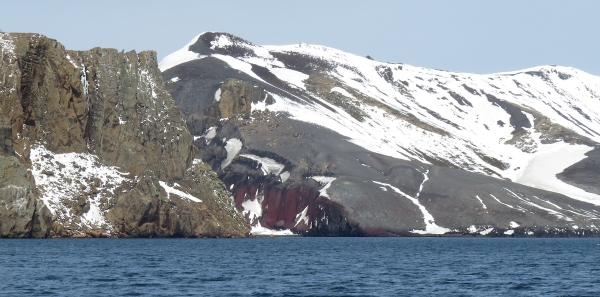 Looking from the caldera back at Neptune's Bellows. On the left are syn-caldera rocks (buff). On the right are post-caldera volcanic products (red and gray). Photo by A. Jefferson.