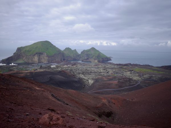 A lava flow viewed from its source volcanic cone, together with the small town it almost engulfed in 1973.
