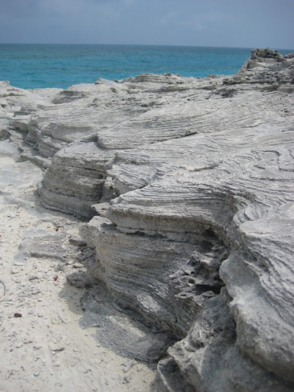 Off-white and grey layers of thinly bedded carbonates on a Bahamas beach