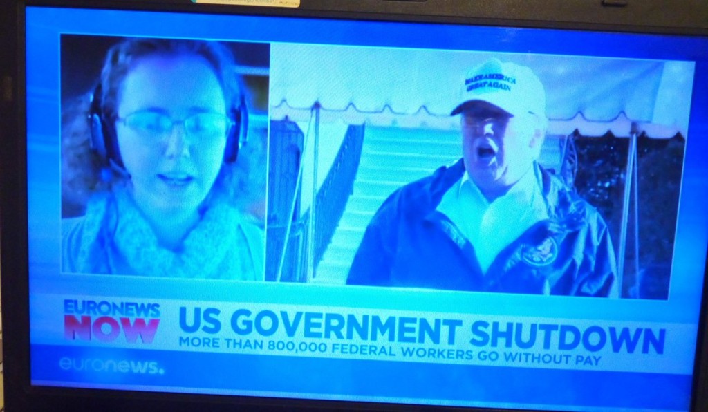 Picture of TV screen, with woman on left and Trump on right, (split screen), banner says "US government shutdown."