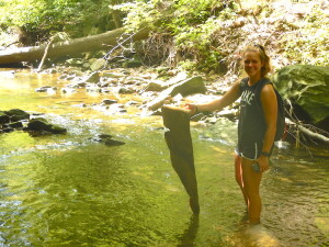 Woman in shorts stands in stream with large piece of metal